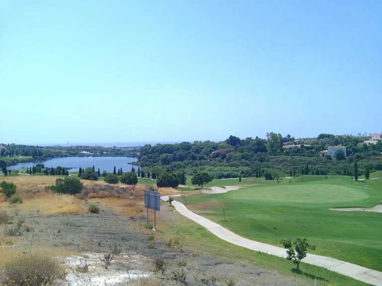 Golf course with a cart path, and a lake in the valley beyond