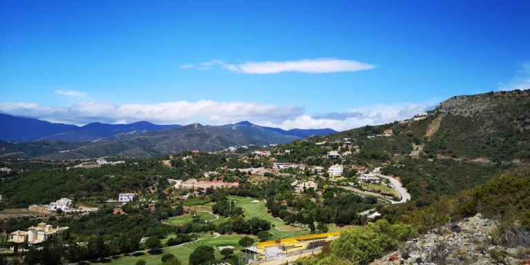 Villas and golf fairways on wooded slopes, with mountains in the distance